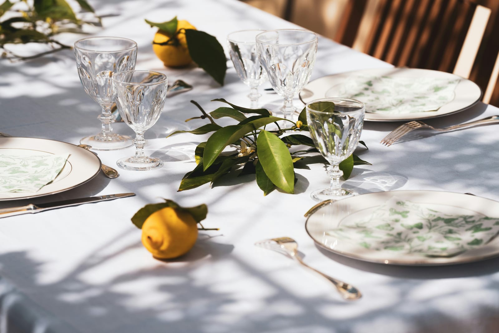 Ein gedeckter Tisch mit Kristallgläsern und Zitronen im Sonnenlicht