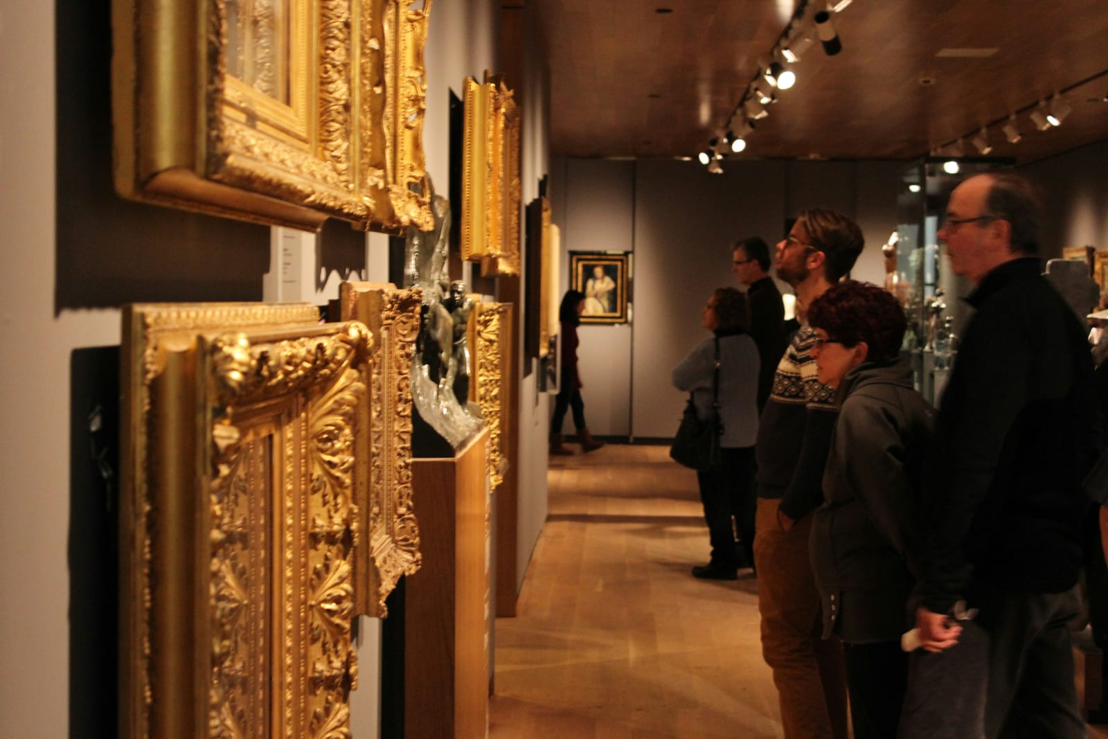 Besucher betrachten vergoldete Gemälderahmen in einem Museum