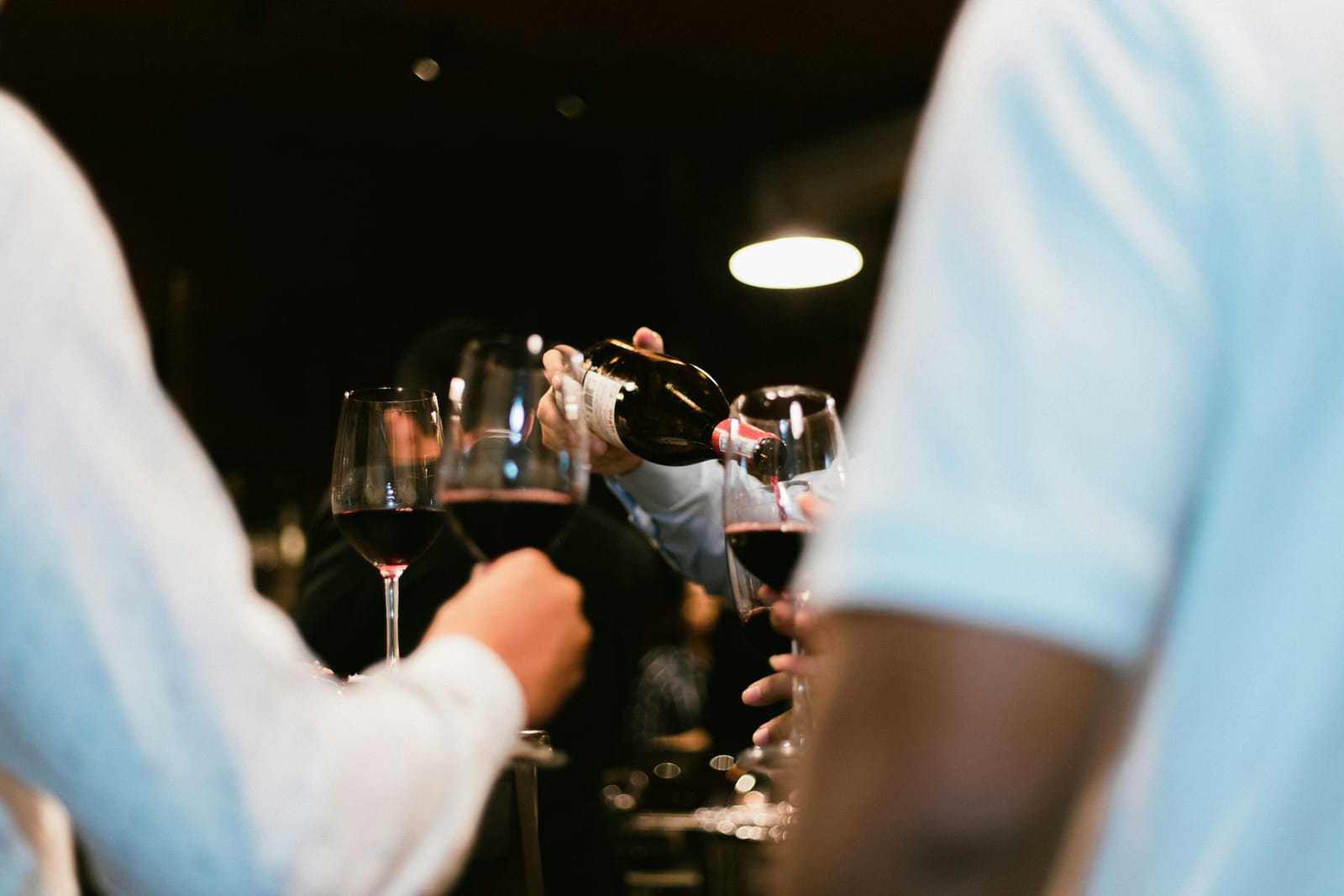 Rotwein wird bei einer Weinprobe in Gläser eingeschenkt